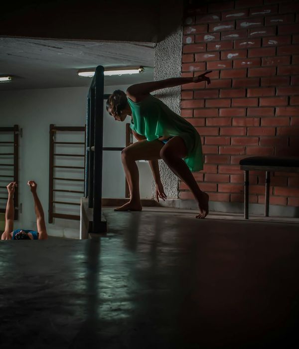 Woman performing a fluid, dynamic movement in a dark studio with emerald light trails.